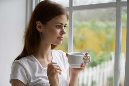 woman at home near the window with a cup of coffee interior vacation morningの写真素材