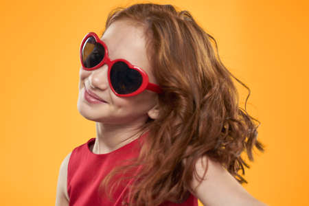 girl wearing heart shaped sunglasses red dress studio yellow background childhoodの写真素材