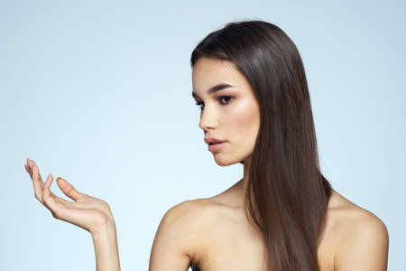 Woman with naked shoulders long hair clean skin cropped view blue backgroundの写真素材