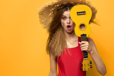 Woman holding Ukulele straw hat lifestyle Exotic yellow backgroundの写真素材