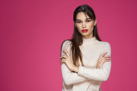 Woman with red lips bright makeup white blouse long hair pink backgroundの写真素材