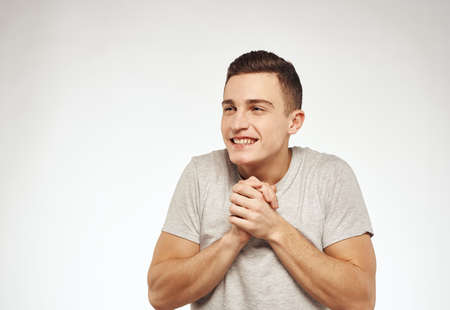 handsome man in a t-shirt gesturing with his hands emotions studio light background