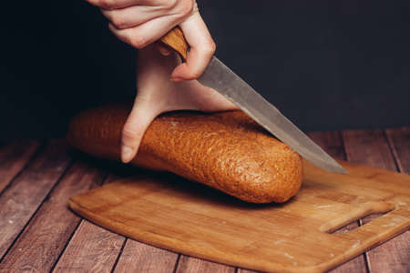 slicing fresh bread on a wooden cutting board breakfastの写真素材