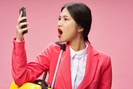 Asian woman with mobile phone on pink background