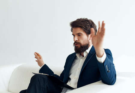 Business man gesturing with his hands in a classic suit Sitting on a sofa indoorsの写真素材