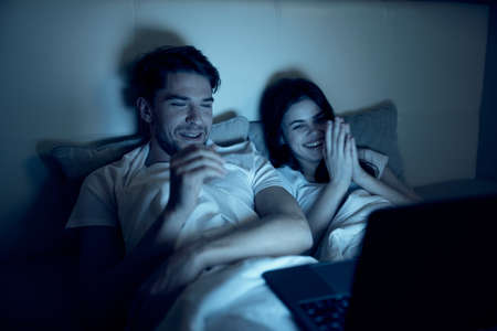 young couple in bedroom at night in front of laptop watching movies