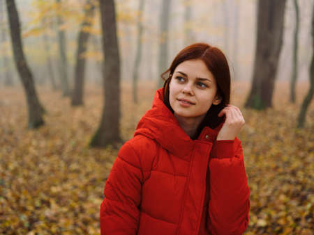 beautiful woman in a red jacket in the autumn forest in natureの写真素材