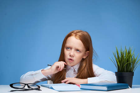 Girl sitting at the table and doing school education lessonsの写真素材