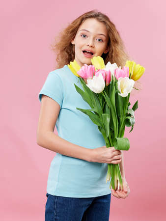 girl with curly hair bouquet of flowers fun pink background holidayの写真素材