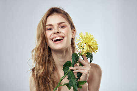 Portrait of a beautiful woman with a yellow flower on a light background cropped with Copy Space Modelの写真素材