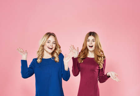 Two pretty women fun emotions elegant communication style pink backgroundの写真素材