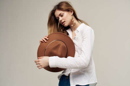 elegant woman in white shirt holding hat in her hands fashion light backgroundの写真素材