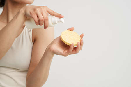 Woman in white t-shirt holds sponge with cream skin care close-upの写真素材