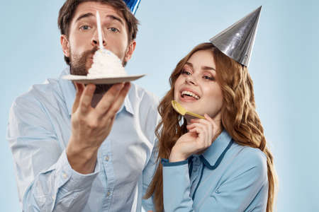 Cheerful man and woman with cake in a plate corporate party blue backgroundの写真素材