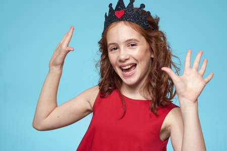 Girl with curly hair with a crown on her head red dress lifestyle blue backgroundの写真素材