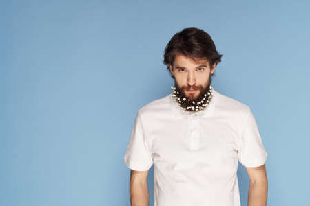 Bearded man with flowers in his hair ornaments fun white t-shirt blue backgroundの写真素材