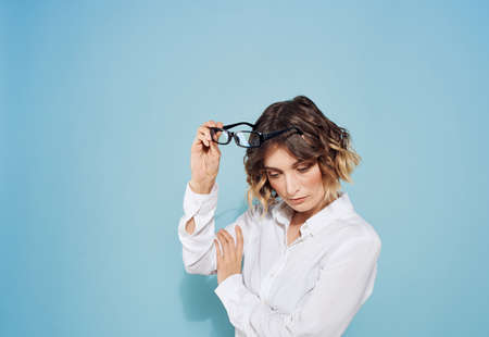 Fashionable woman curly hair short haired glasses and white shirt blue backgroundの写真素材