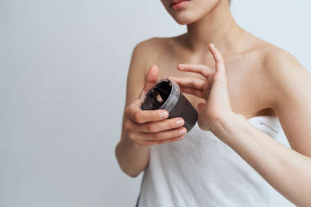 Woman in towel bared shoulders black cream in clean skin handsの写真素材