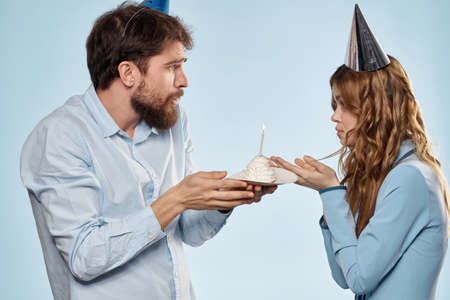 Cheerful man and woman with cake in a plate corporate party blue backgroundの写真素材
