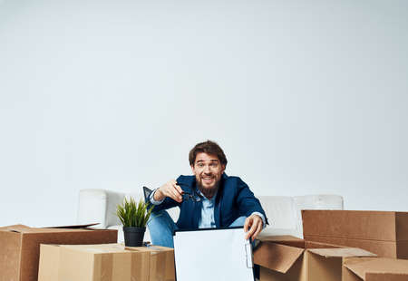 Business man sitting on the floor with boxes unpacking documents to the office managerの写真素材