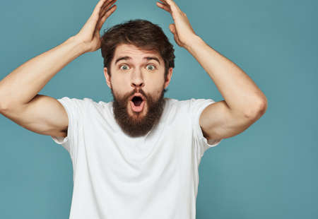 joyful man touching his head with his hands happiness emotions blue backgroundの写真素材