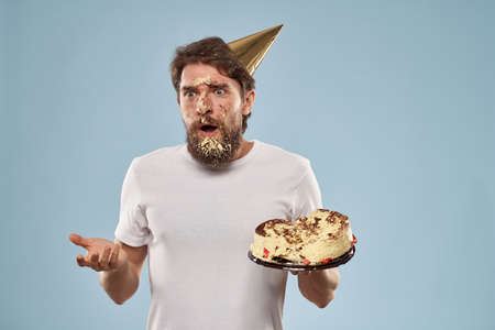 Bearded man in a holiday cap Birthday cake emotionsの写真素材