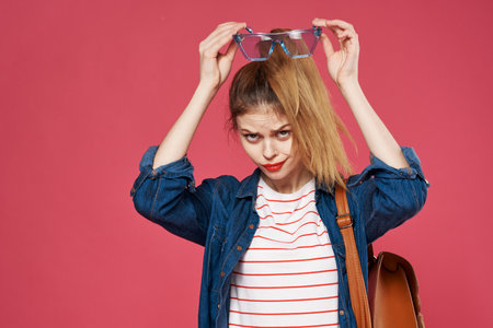 fashionable woman holding backpack clothes student learning pink backgroundの写真素材