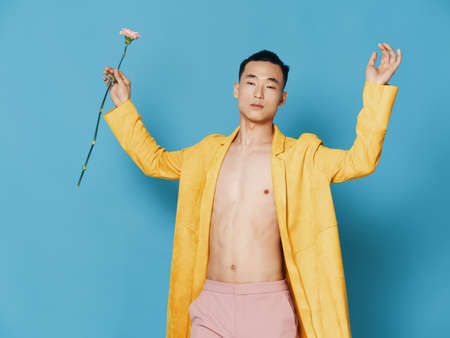 Guy with a flower in his hand on a blue background and an unbuttoned jacket cropped viewの写真素材