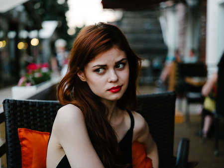 Beautiful red-haired woman at a table in a cafe model close up portrait streetの写真素材