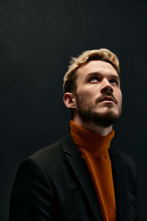 stylish blond guy in fashionable clothes on a dark background orange sweater jacket model close-upの写真素材