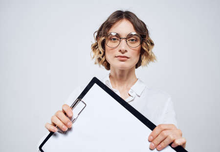 Business woman holds in her hands a folder with a white sheet on a light background mockup