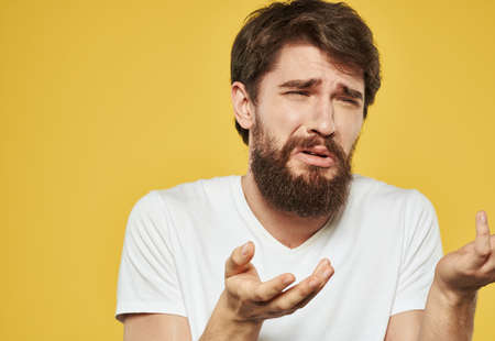 Upset guy crying on a yellow background and gesturing with his hands