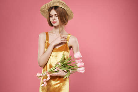 Beautiful woman golden dress and bouquet of flowers holiday elegant style pink background