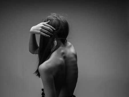 Black and white photo of a long hair model touching herself with hands
