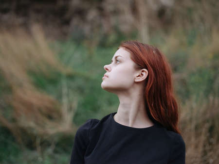 Portrait of a woman in a black dress outdoors on a meadow in the mountains