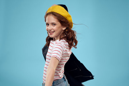 Cheerful cute girl in yellow hat clothes studio blue background
