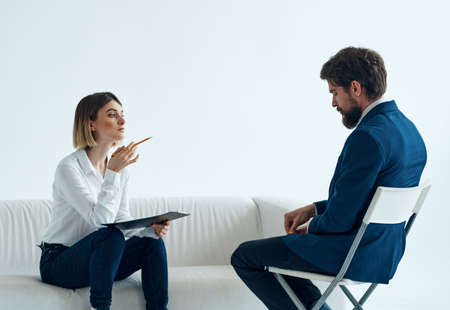 A woman psychologist with documents sits on the couch and a manの写真素材