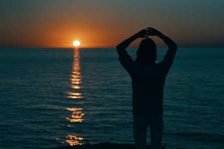 female silhouette on the beach near the sea at sunsetの写真素材