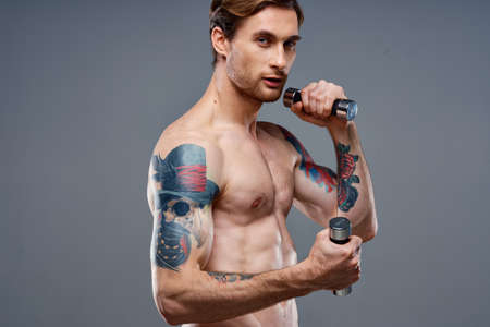 male athlete with a tattoo on his arm naked torso inflated muscles dumbbells fitnessの写真素材