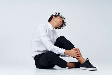 man with curly hair in a classic suit and sneakers sits on the floor and side view Copy Spaceの写真素材