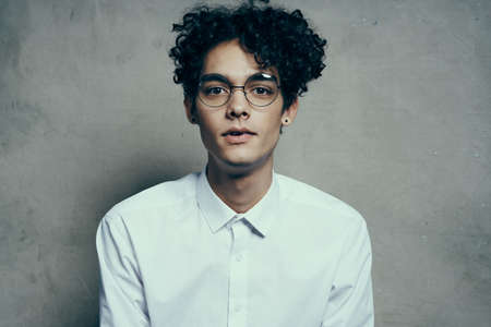 portrait of a happy guy with glasses curly hair white shirt photoshoot modelの写真素材