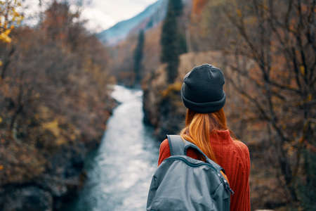 woman with backpack in nature on the bridge near the river mountains adventureの写真素材