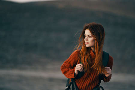 pretty woman in a sweater with a backpack on her back are resting in the mountains in natureの写真素材