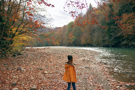 woman in a yellow jacket near the river mountains nature walkの写真素材