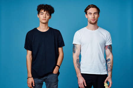 two men in t-shirts on a blue background and pants chatting friendsの写真素材