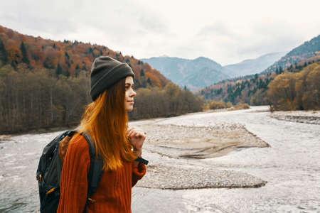 beautiful traveler with a backpack near the river in the mountains on nature landscapeの写真素材