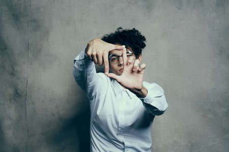 fashionable guy with curly hair gesturing with his hands on a gray background portrait close-upの写真素材