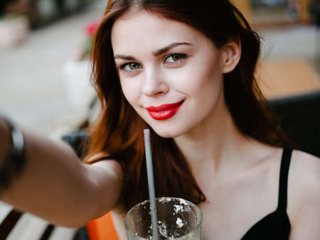 Beautiful red-haired woman at a table in a cafe model close up portrait streetの写真素材