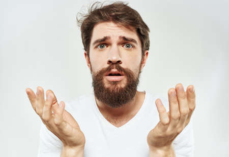 A man gestures with his hands on a light background in a white t-shirt cropped viewの写真素材