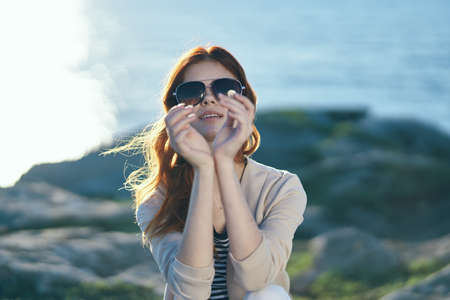 happy woman in glasses travels on nature in the mountains near the sea at sunset cropped view